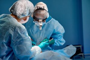 Two surgeons wearing surgical scrubs and performing an operation.