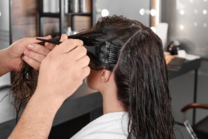 A woman getting dye put in her hair by a hairdresser.