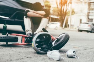 A child and their bike on the road in front of a car. 