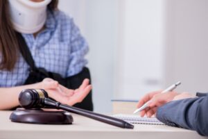 A person wearing a neck brace and with their arm in a sling sits at a table and talks to a construction accident claims solicitor.