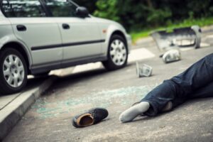 A person lays in the road by a road traffic accident. 