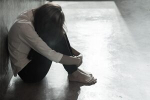 A victim of domestic violence sits on the floor.