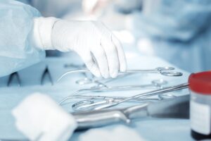 A nurse reaches for surgical instruments.