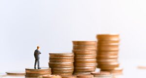 A plastic figure stands on a stack of coins to represent personal injury compensation. 