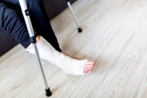 A man sitting at home with his right leg in plaster after breaking it at work.