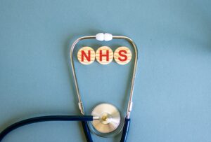 The letters 'nhs' written in red on wooden blocks in the middle of a stethoscope.