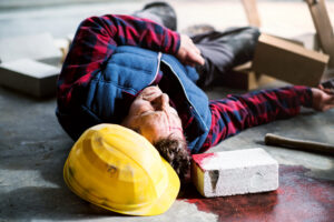 A construction worker laying on the ground having suffered a traumatic brain injury from being hit by a falling brick