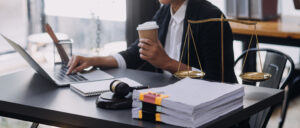 A solicitor researches spine injury claims while drinking coffee at a desk with gavel and scales. 