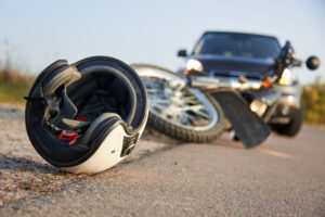 a motorcycle and white helmet laying on the road in front of a black car