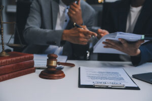 Fatal accident claims solicitors examining documents for an upcoming claim. There is a gavel hammer, set of justice scales and several legal texts on the desk