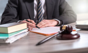 A lawyer sitting besides a table goes over legal documents as he answers questions like "I had an accident at work, what are my rights in the UK?".