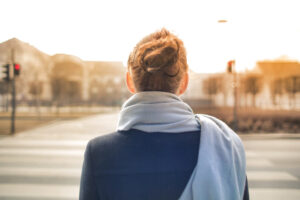 A woman with her back to the camera walks across a street.